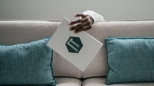 A man holding a book over a couch, the book reads "The Benefits of Branding"